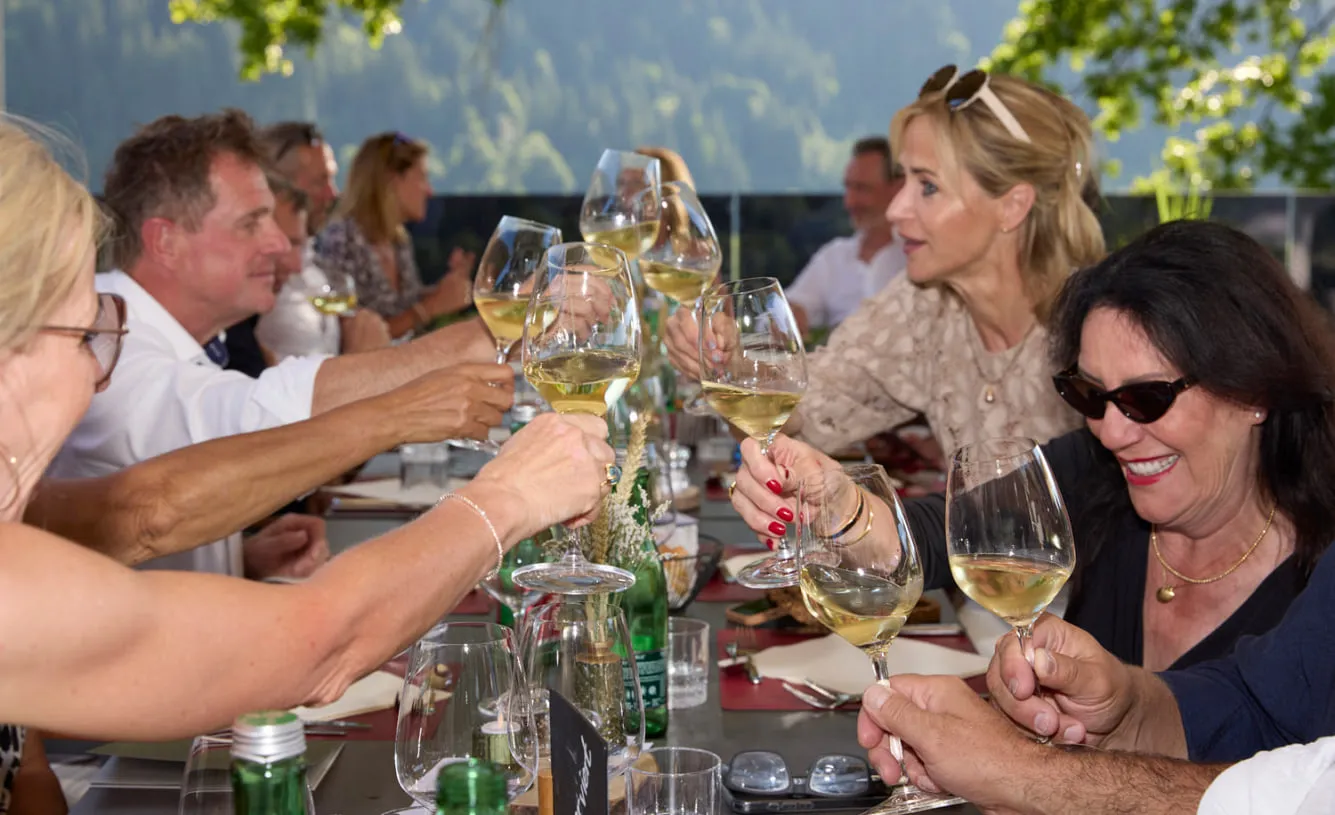 Turniergäste stoßen an einer gedeckten Tafel mit Weißwein an