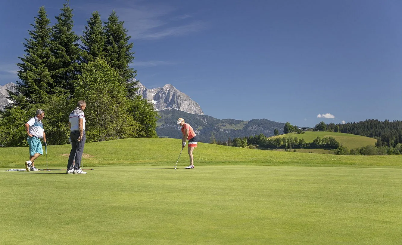 Drei Golfer auf dem Grün, im Hintergrund der Wilde Kaiser