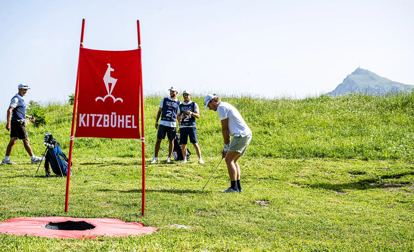 Spieler am Abschlag neben der roten Kitzbühel-Fahne, im Hintergrund das Kitzbüheler Horn