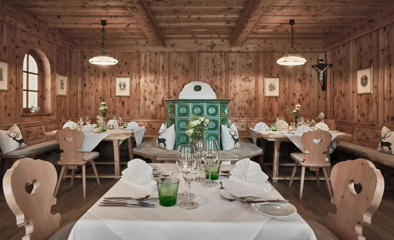 Zirbenstube mit Kachelofen und gedeckten Tischen im Lisi Family Hotel