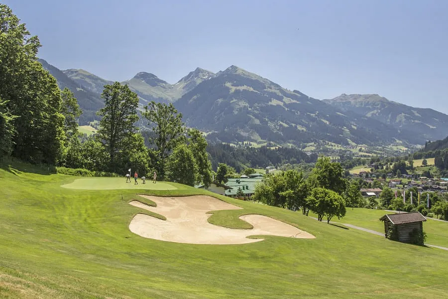 Grün mit großem Bunker am Hang, dahinter Tal und Berge