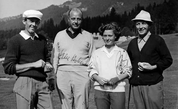 Drei Männer und eine junge Frau nebeneinander auf dem Golfplatz