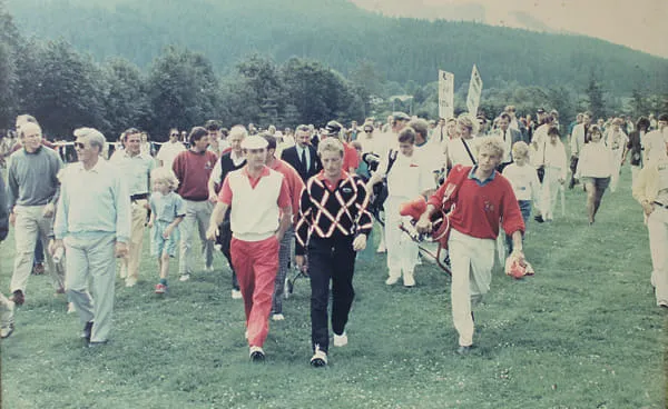 Golfer gehen, von vielen Zuschauern begleitet, über den Golfplatz