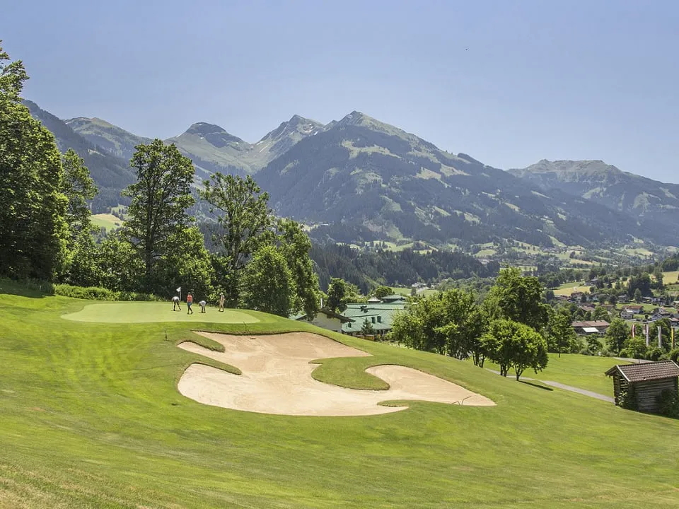 Grün mit großem Bunker am Hang, dahinter Tal und Berge